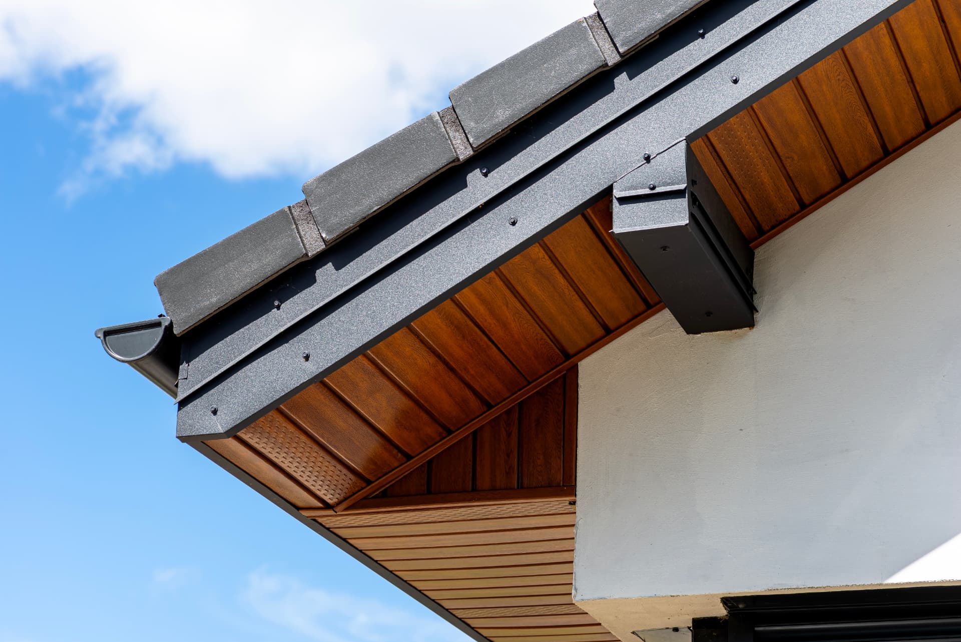 New fascia, soffit and guttering fitted along a roof edge against a blue sky